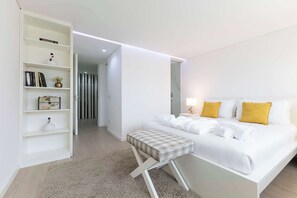 Een moderne hotelkamer met een bed, nachtkastje en een witte plank.