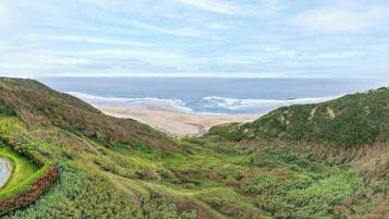 A coastal landscape with a beach, rolling hills, and a clear sky.