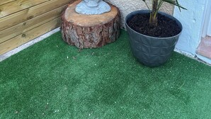 A statue of a seated figure on a wooden stump, a potted plant, and a wooden fence.