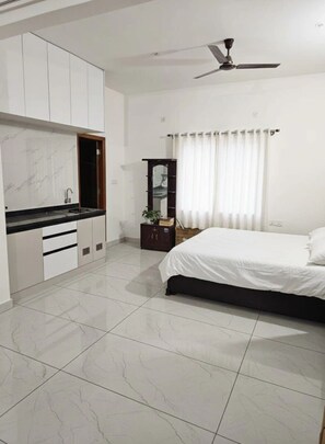 A bedroom with a bed, a ceiling fan, a nightstand, a mirror, and a window with curtains. - Penthouse, Lakeview, AirportRoad (Bengaluru)