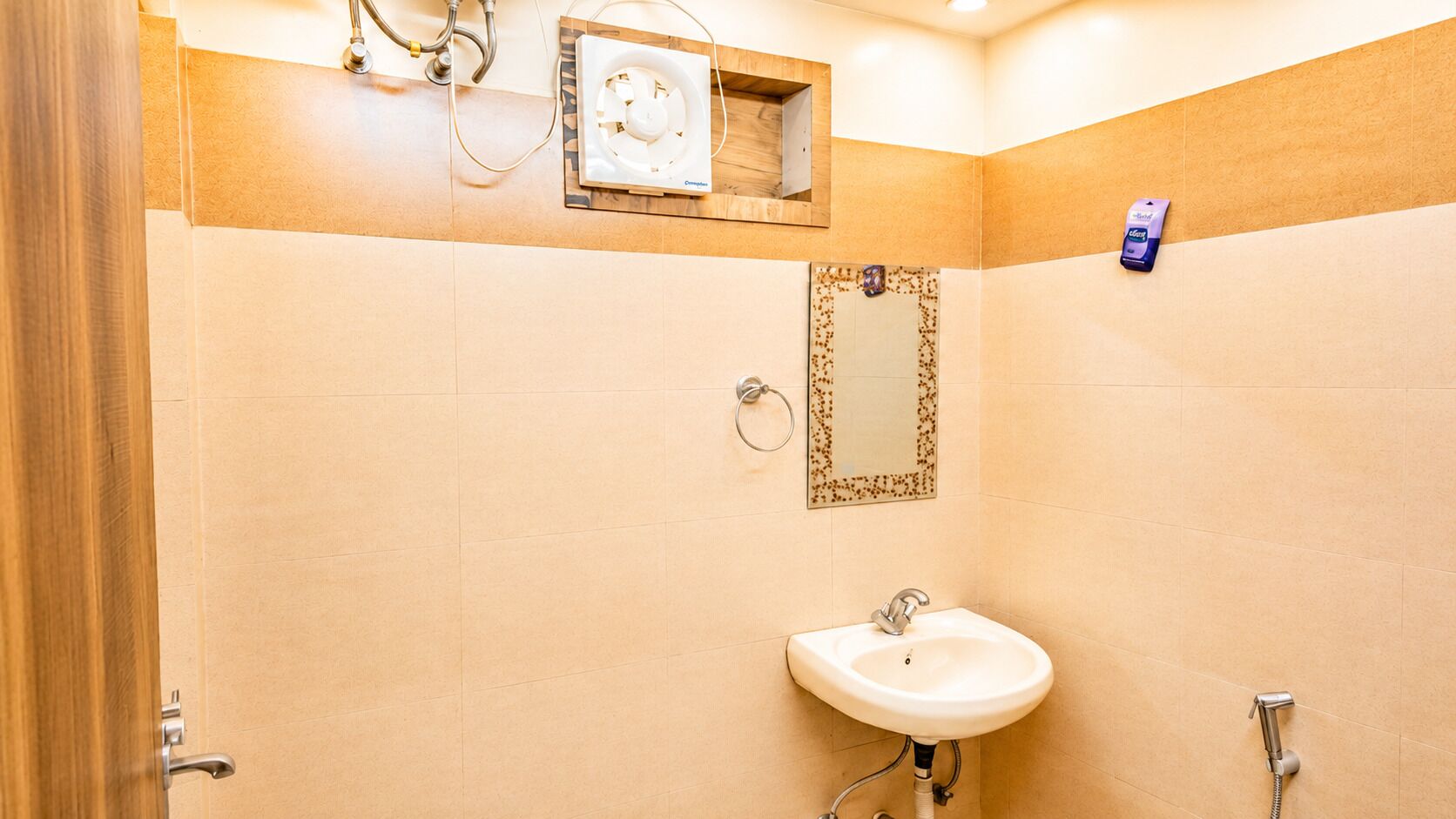 Une salle de bain équipée d’un lavabo, d’un miroir et d’un ventilateur.