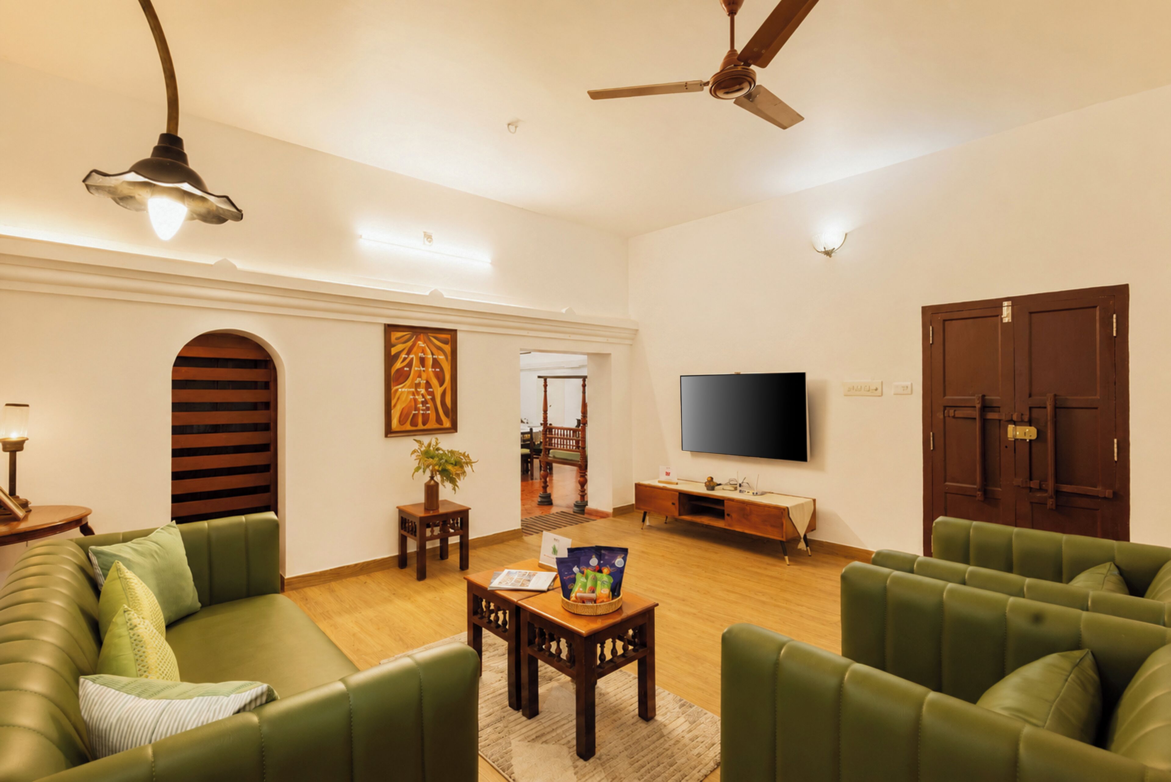 Un salon avec un canapé vert, une table basse, un téléviseur et un ventilateur de plafond.
