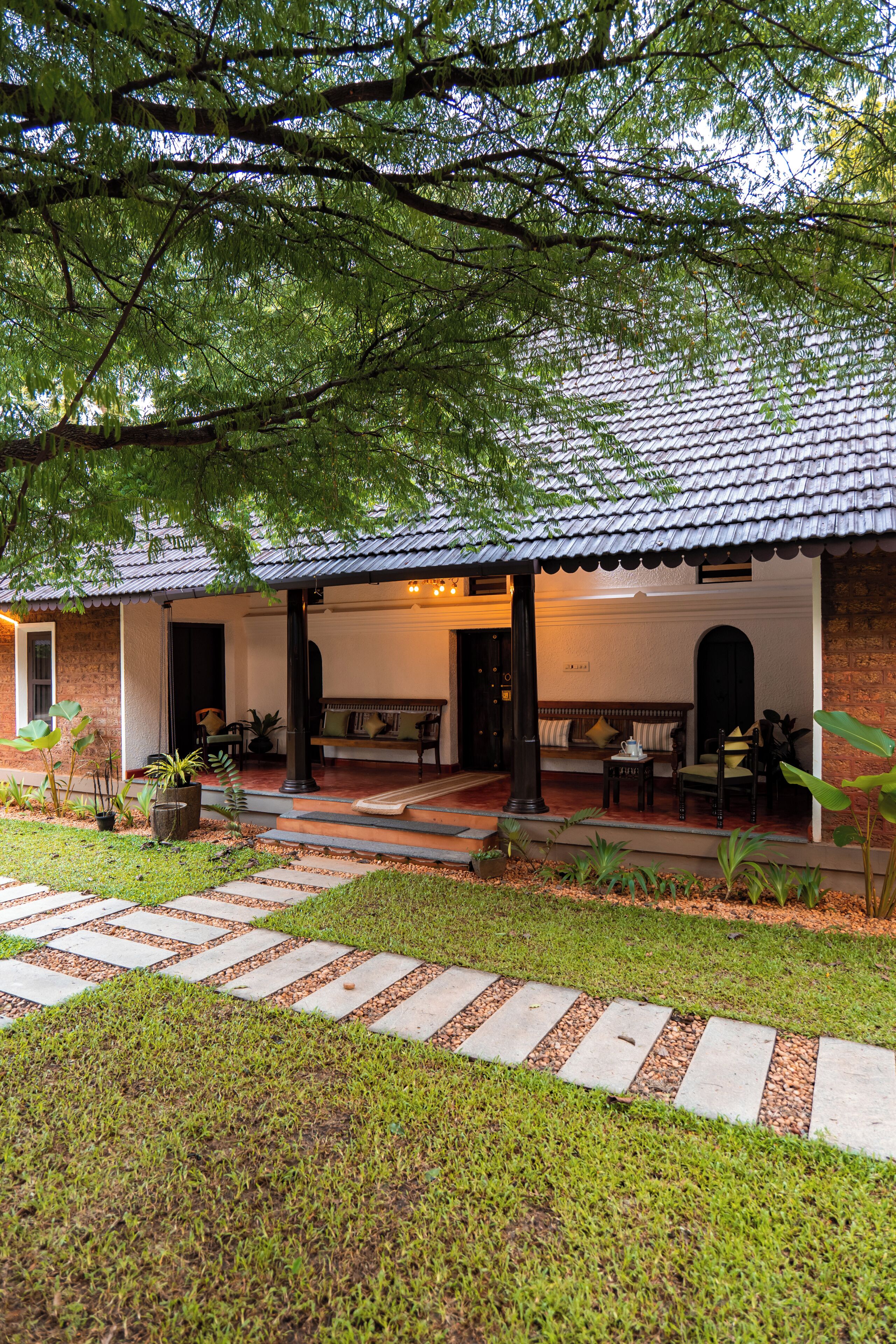 Una casa con porche, mobiliario exterior y un sendero en el jardín.