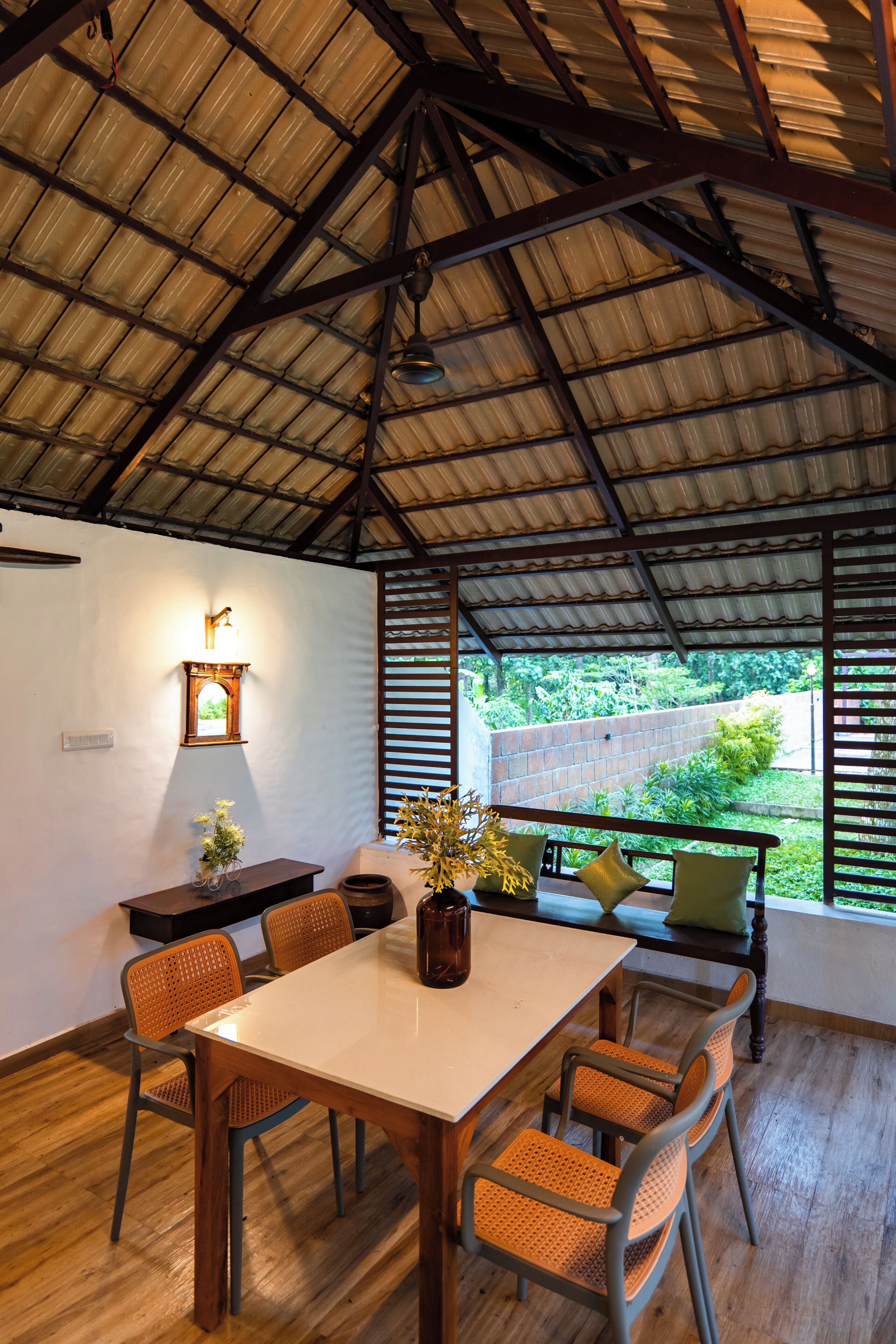 A dining area with a table, chairs, and a view through large windows.