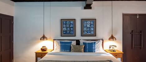 A bedroom with a bed, two nightstands, a ceiling fan, and two framed wall art pieces.