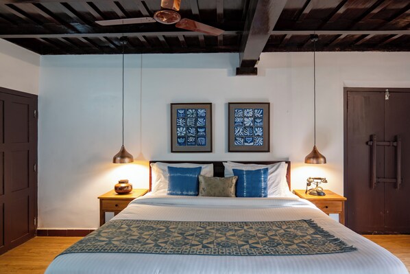 A bedroom with a bed, two nightstands, a ceiling fan, and two framed wall art pieces.