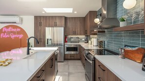 Uma cozinha moderna com uma ilha central, eletrodomésticos embutidos e um letreiro de neon.