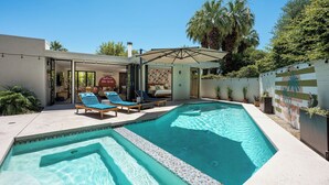 Piscina com espreguiçadeiras, um terraço coberto e uma casa com interior visível.