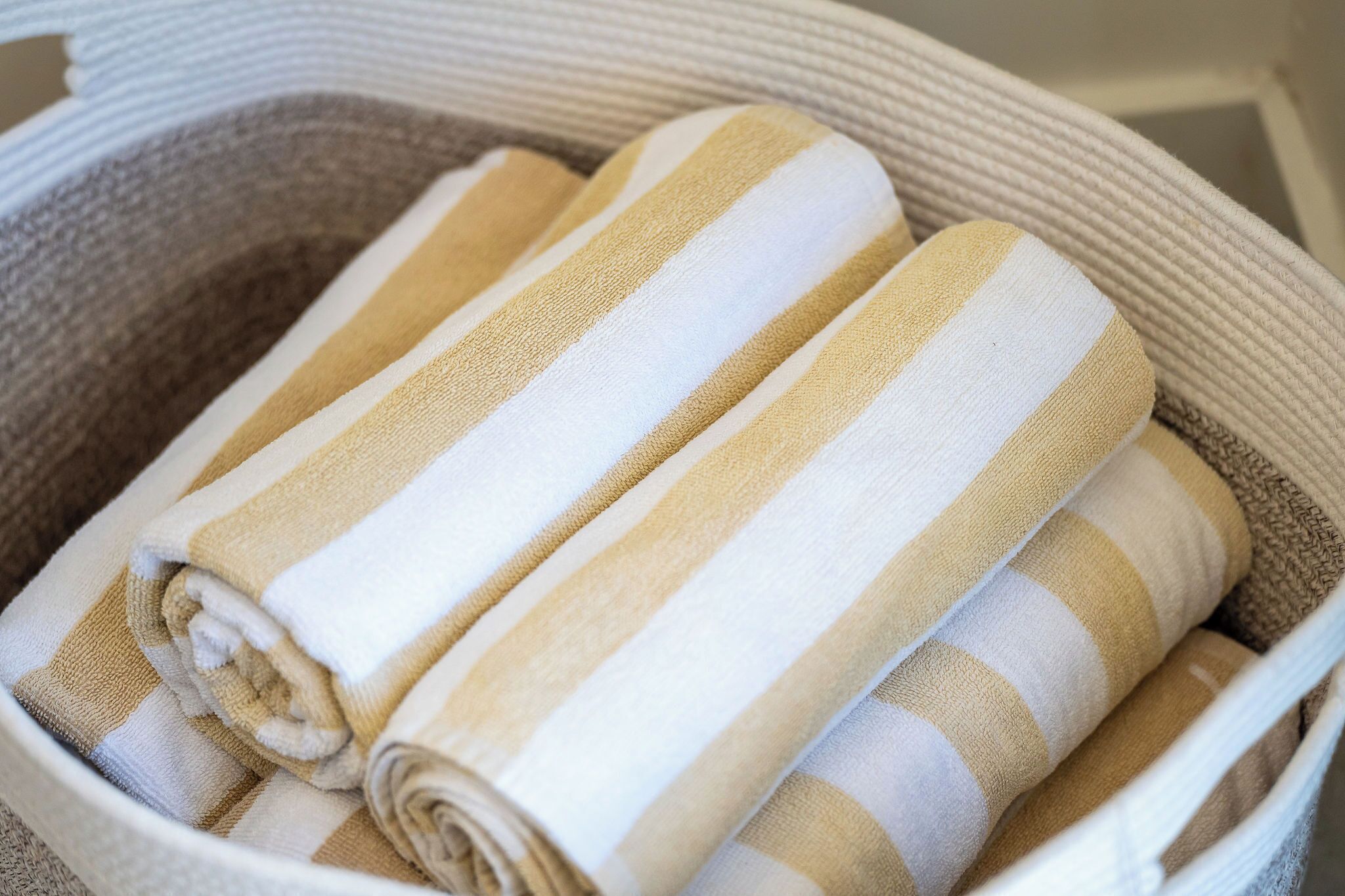 Un panier contenant des serviettes enroulées et ornées de motifs à rayures.