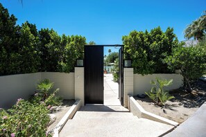 Ein begrenzter Eingang mit einem Betonweg, der zu einem Gebäude führt.
