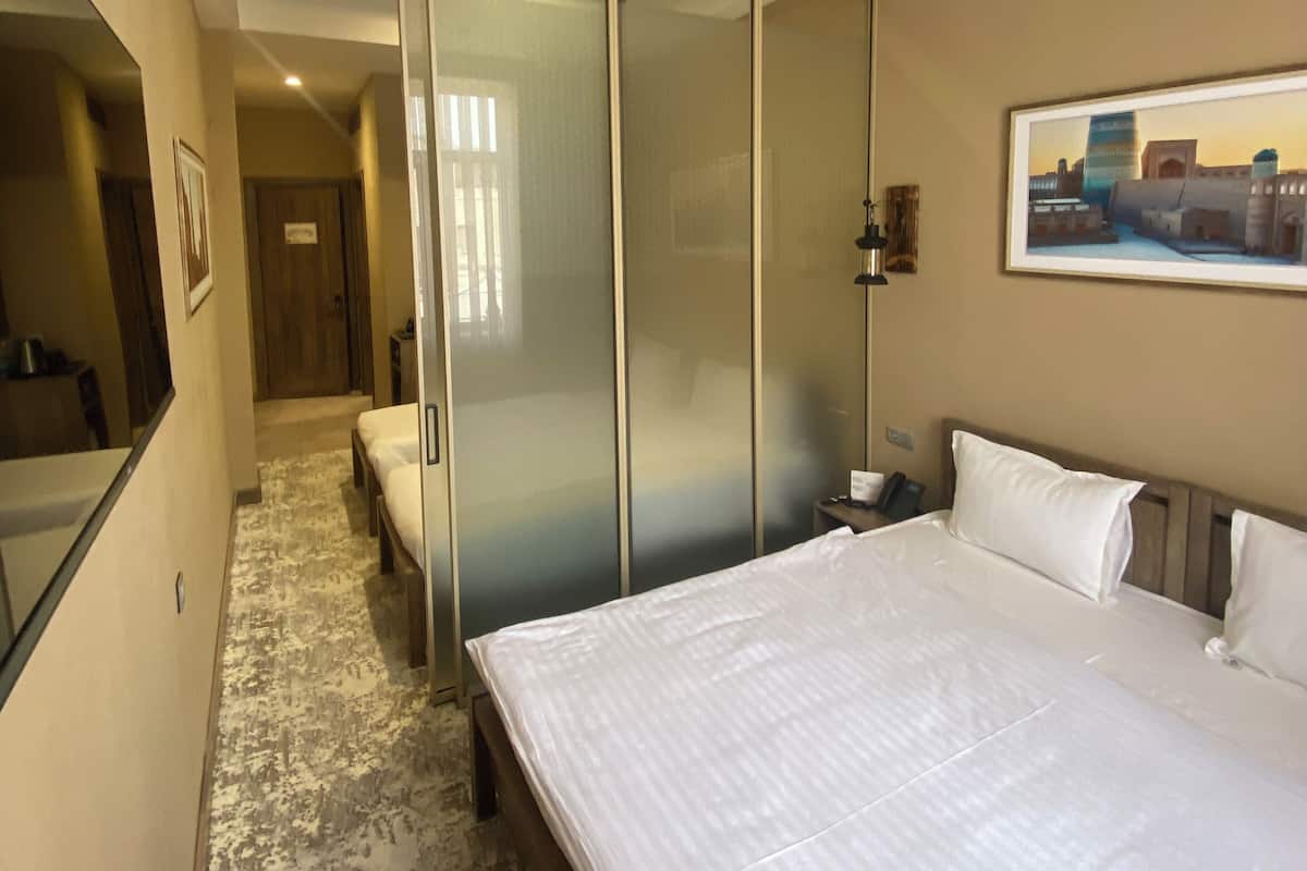 Une chambre d’hôtel comprenant un lit, un placard avec porte coulissante, une table de chevet, un tableau encadré au mur et un sol recouvert de moquette.