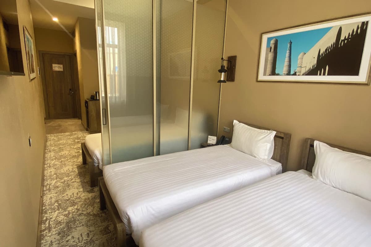 Une chambre d’hôtel avec deux lits, un grand miroir, un tableau et un sol recouvert de moquette.