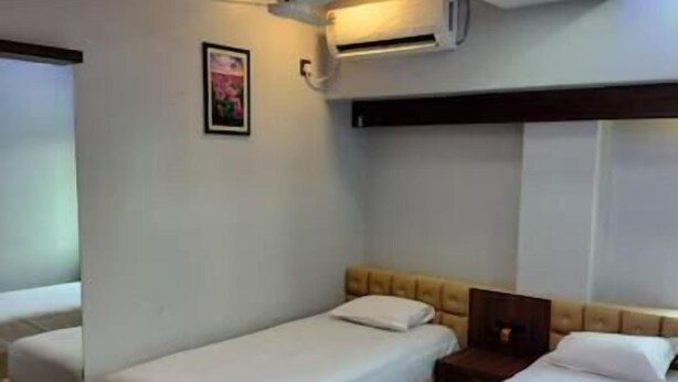 A hotel room with two single beds, a desk, a chair, a small table, an air conditioning unit, a ceiling fan, and a framed picture on the wall. - Hotel Epar Bangla (Agartala)
