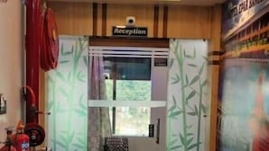A reception area with a 'Reception' sign, a welcome mat, potted plants, a fire extinguisher, and a chair. - Hotel Epar Bangla (Agartala)