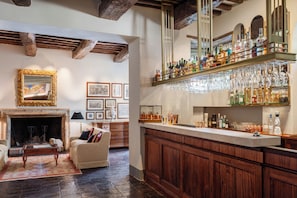 A bar area with a wooden counter, shelves with bottles, and hanging glasses.