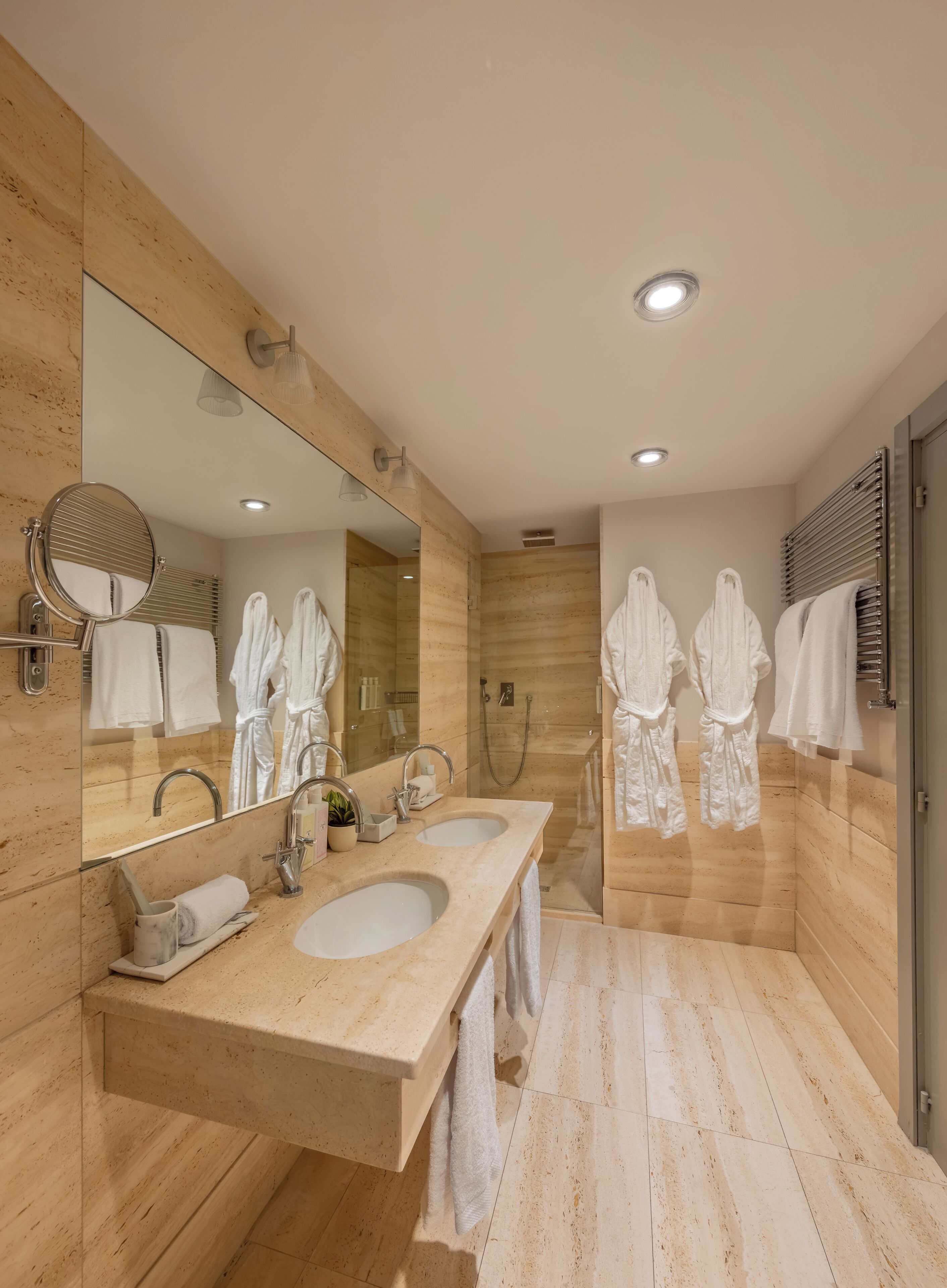 Un bagno moderno con due lavabi, uno specchio grande e una zona doccia.