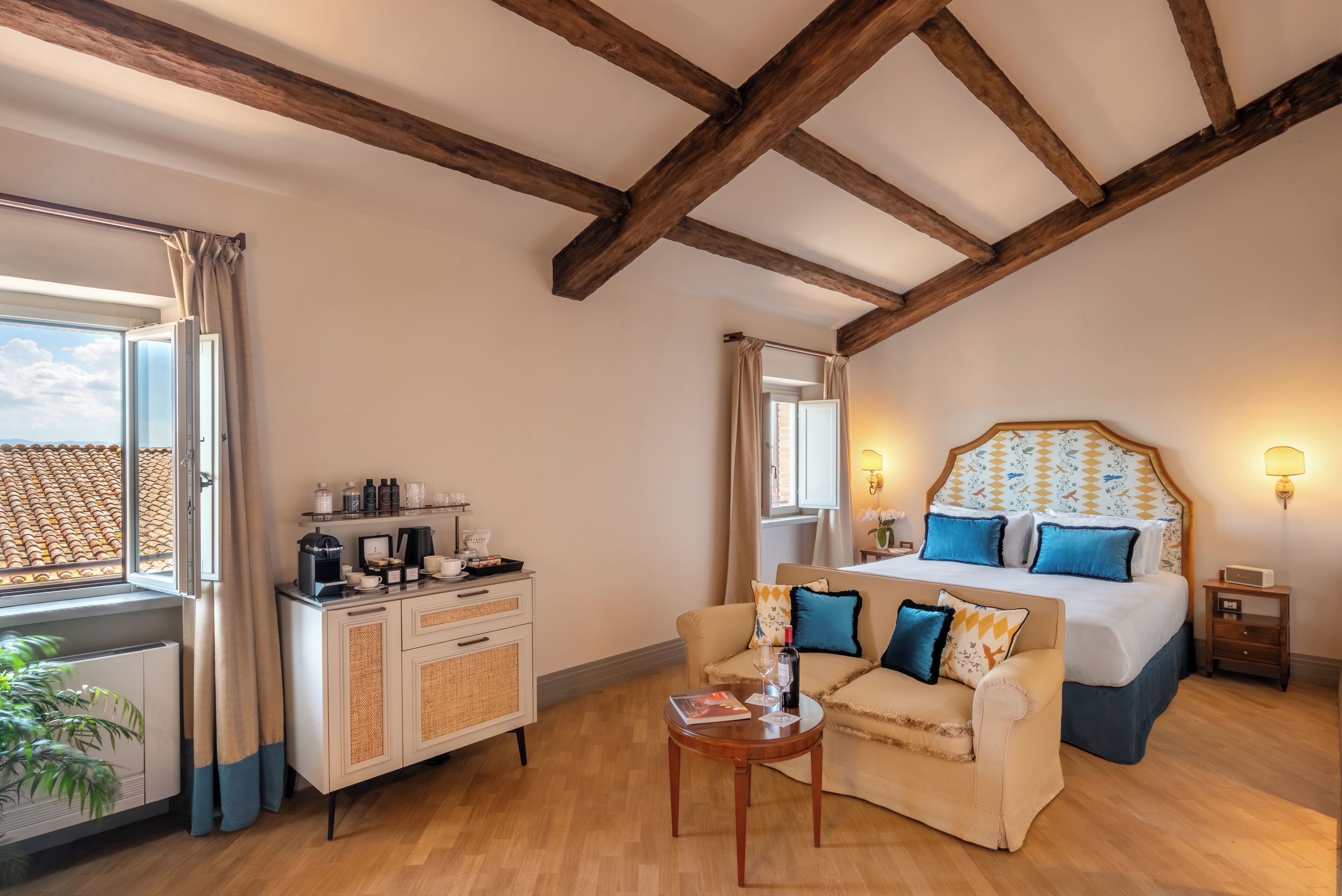 Een slaapkamer met een bed, een bank, een salontafel, een nachtkastje en een raam met gordijnen.