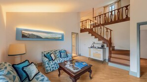 A spacious living area with a sofa, a coffee table, a painting, and a staircase.