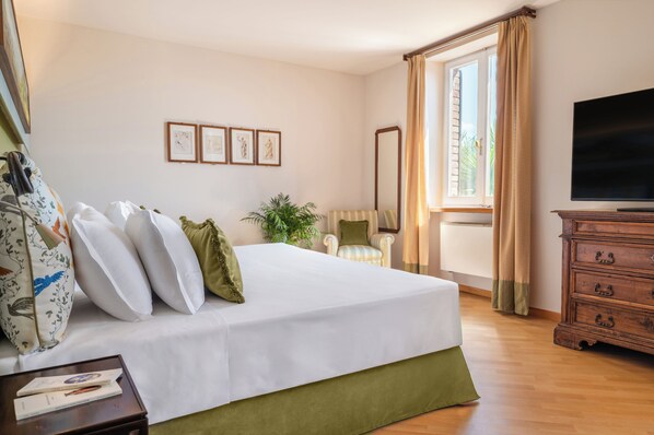 A hotel room with a bed, a television, a dresser, a chair, and framed pictures on the wall.
