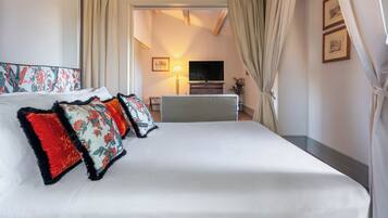 A hotel room with a large bed, a television, a desk, and a lamp.