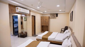 A hotel room with two beds, a ceiling fan, an air conditioning unit, and a wooden accent wall. - Park View Residency (Bhuj)
