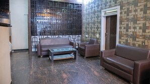 A lobby with a brown leather sofa, a glass coffee table, and a patterned wall. - Park View Residency (Bhuj)
