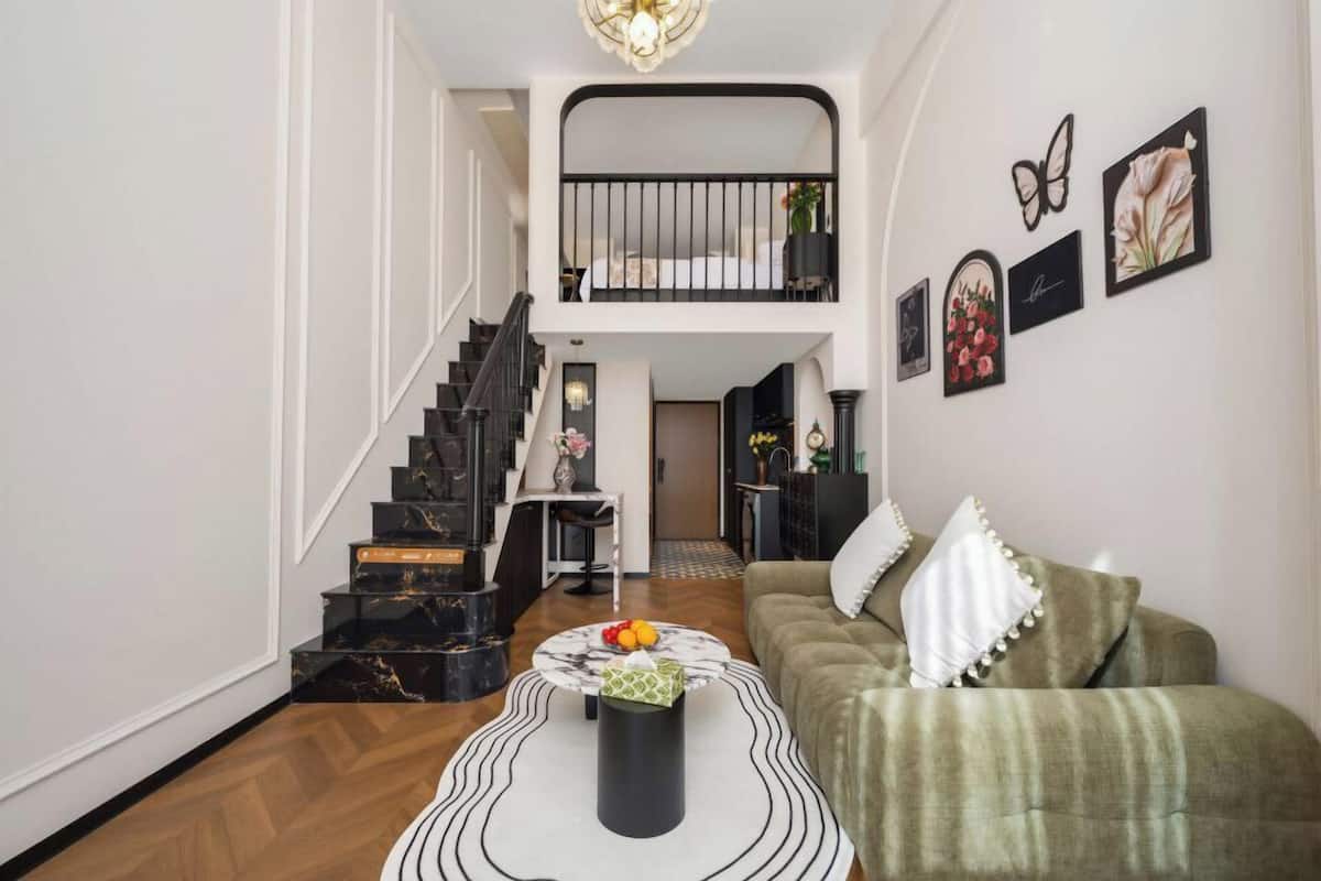 Um interior moderno com escada, área de jantar e sala de estar com sofá e mesa de centro.
