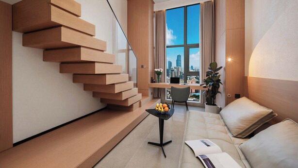 Un apartamento moderno con una escalera flotante, vistas a la ciudad, un sofá y una pequeña mesa con frutas.
