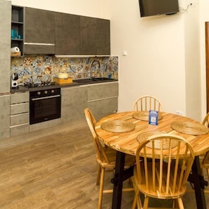 A compact kitchen with a dining table, chairs, and a TV mounted on the wall. - Prima Classe Battipaglia (Battipaglia)