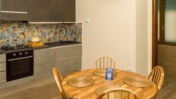 Una cocina moderna con salpicadero de azulejos, un televisor de pantalla plana y un comedor con una mesa y sillas de madera.