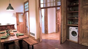 Una cocina rústica con armarios de madera, una mesa de comedor con platos y vasos, y una lavadora en la esquina.