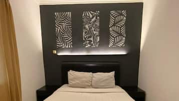 A neatly made bed with a headboard, a bedside table, and a wall-mounted light fixture.