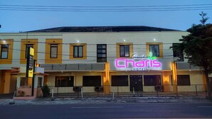 A hotel with a neon sign, multiple windows, and a visible entrance.