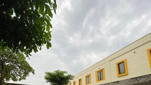 A hotel with a brick-paved courtyard, parked cars, and a building with yellow trim.