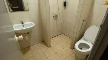A small bathroom with a toilet, sink, and shower.