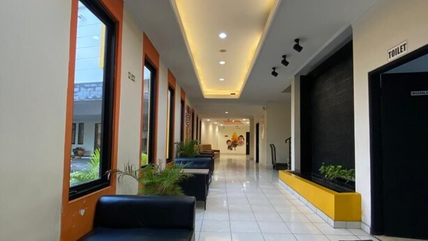 A hotel corridor with seating, a visible toilet, and a window with a view.