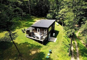 Eine kleine Holzhütte mit einer Veranda, umgeben von dichtem Wald.