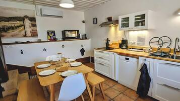 Uma cozinha compacta com mesa de jantar posta para quatro pessoas, lava-louças e micro-ondas.