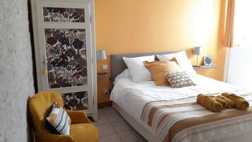 Hotelkamer met een bed, een stoel, een nachtkastje met lamp en een bloemen behang.