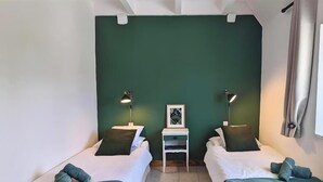 Une chambre avec deux lits, une petite table et deux lampes de chevet.