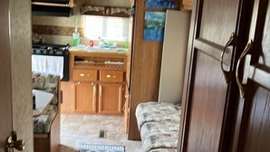Cocina compacta para camper con microondas, estufa y armarios de madera.