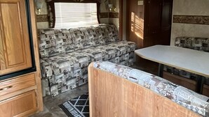 Cocina compacta para autocaravana con armarios de madera, un sofá estampado y una pequeña encimera.