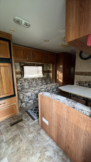 A compact RV kitchen with wooden cabinets, a patterned sofa, and a small countertop.