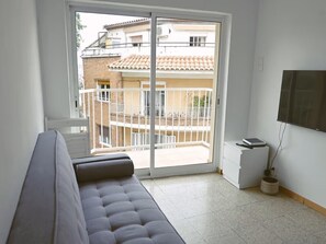 A room with a sofa, a TV, a small white cabinet, and a sliding glass door leading to a balcony. - Homenfun Barcelona Park Guell (BARCELONA)
