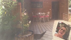 Un patio con mesa y sillas, un muro de ladrillo y una planta en maceta.