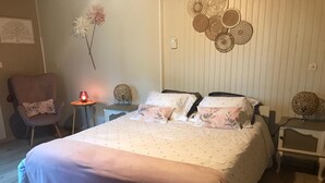 Un dormitorio con cama, una silla, una mesita de noche, una lámpara y decoración en la pared.