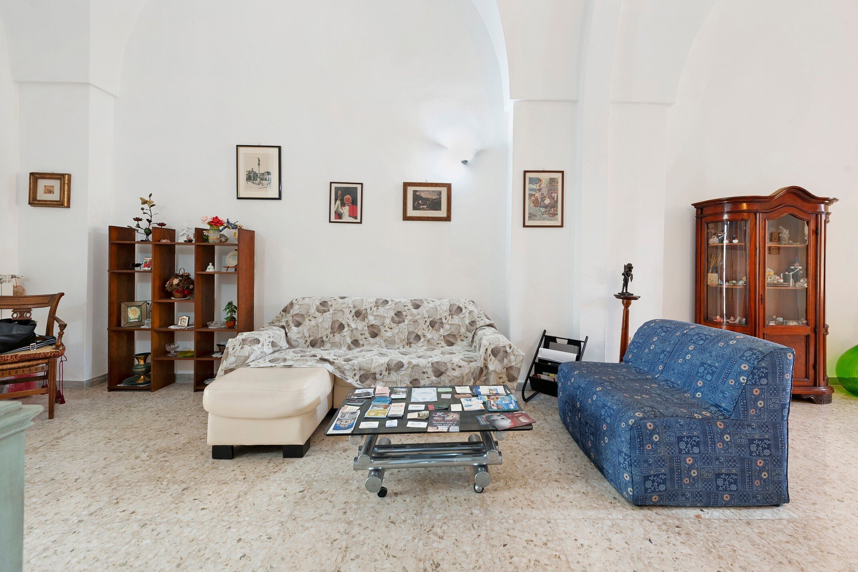 A living room with a sofa, ottoman, coffee table, and a cabinet with glass doors.