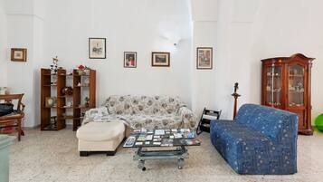 A living room with a sofa, ottoman, coffee table, and a cabinet with glass doors.
