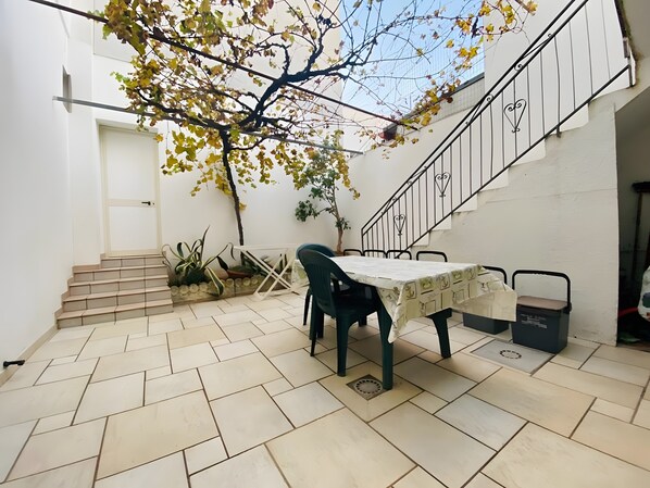 Une terrasse avec une table et des chaises, un escalier et des plantes en pot.