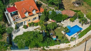 Vue aérienne d’une propriété dotée d’une piscine, d’un bâtiment au toit rouge et d’un mur en pierre.
